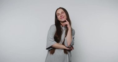 Stüdyoda düşünceli bir ifadeyle şakacı bir şekilde düşünen genç bir kadın.