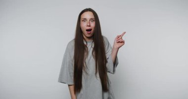 Basit bir stüdyo ortamında uzun saçlı genç bir kadının şaşırtıcı tepkisi.