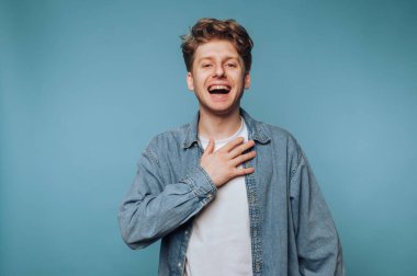 Genç adam göğsünde mavi arka planla gülüyor..