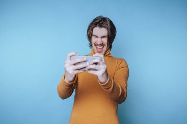 Hardal kazaklı genç adam seyyar oyun oynuyor, heyecanlı bir ifade..