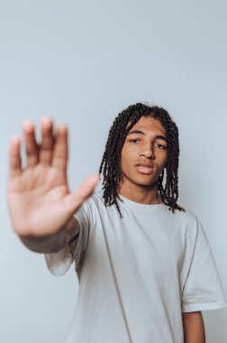 Rastalı genç adam elleriyle bir dur hareketi yapıyor..