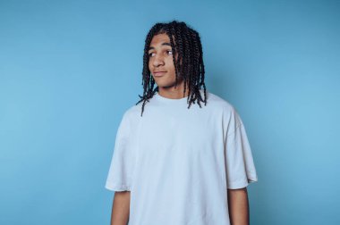 Mavi arka planda beyaz tişörtlü örgülü genç adam..