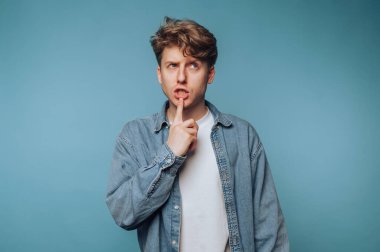 Kot gömlekli genç adam parmaklarıyla dudaklarını mavi arka planda gezdiriyordu..