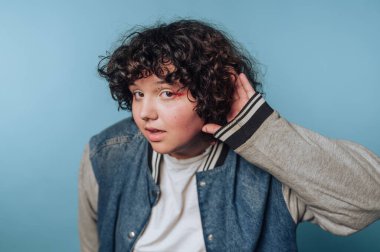 Mavi arka planda kot ceketli kıvırcık saçlı bir genç..