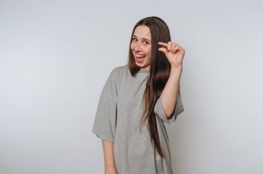 Uzun saçlı genç bir kadın parmaklarıyla hareket ediyor, gülümsüyor..