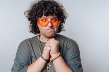 Kıvırcık saçlı, turuncu güneş gözlüğü takan, renkli bilezikler takan, el sıkışan biri..