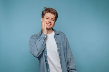 Mavi arka planda el ele gülümseyen genç adam..