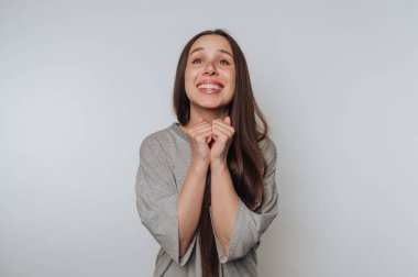 Uzun saçlı, gri gömlekli neşeli bir kadın heyecanını dile getiriyor..