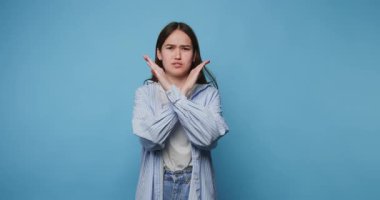 Mavi arka planda işaret dili kullanan genç bir adam önemli bir mesaj vermek için günlük kıyafet giyiyor.