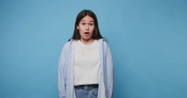 Etkileyici bir şokla genç bir kadın duygularını parlak mavi bir arkaplana karşı paylaşıyor.