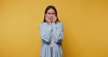 Kadın, gündelik bir ortamda parlak sarı bir arkaplan karşısında kaygılarını dile getiriyor. Duygularını ve vücut dilini gösteriyor.