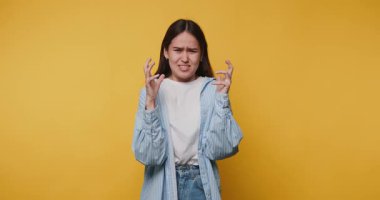 Stüdyodaki parlak sarı arka planlı genç bir kadının hayal kırıklığının duygusal ifadesi.