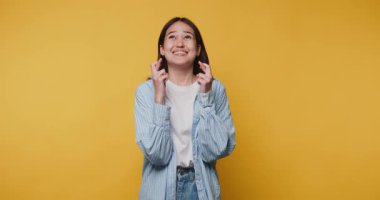 Neşeli genç kadın, parlak sarı arkaplan önünde umut ve heyecanı ifade ediyor.