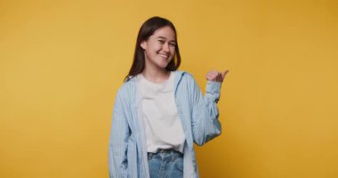 Parlak sarı bir zemin üzerinde mutlu bir şekilde el kol hareketi yapan genç bir kadın, parmağıyla kenarı işaret ediyor.