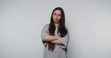 Kollarını kavuşturup düşüncelerini basit ve temiz bir arkaplanda paylaşan bir kadın. Yüzündeki ifade samimiyet ve düşünceliliği yansıtıyor..