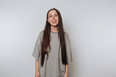 Genç bir kadının portresi sıcacık gülümsüyor, ışık arka planında pozitiflik ve kendine güven yayıyor.