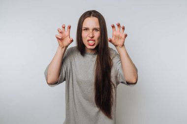 Gri tişörtlü genç bir kadının portresi çarpıcı bir şekilde açık arkaplanda poz veriyor.