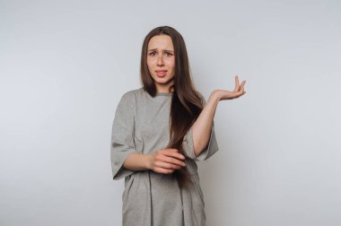 Genç bir bayanın hoşnutsuzluğunun portresi hafif arka planda bir sorgulama jesti olarak elini kaldırıyor.