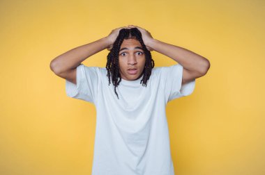 Genç bir adamın portresi, sarı arka planda şaşkınlık içinde, geniş gözlerle başını tutar.