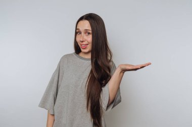 Uzun saçlı genç bir kadının portresi neşeli bir şekilde elini uzatıyor, ışık arka planında neşe ve pozitiflik sergiliyor.