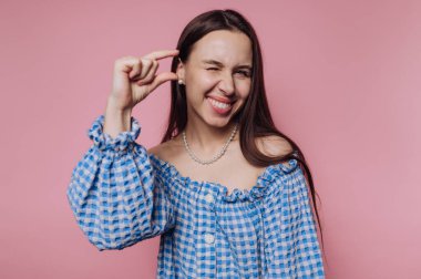 Genç bir kadının portresi, pembe arka planda küçük bir şey sergiliyor.