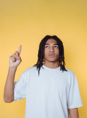 Genç adamın portresi, sarı arka plandaki bir fikri sembolize eden tuhaf bir ifadeyle parmağını kaldırır.