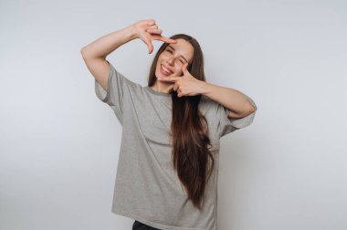 Neşeli genç bir kadının portresi, elleriyle bir sahneyi canlandırıyor, yaratıcılığını gösteriyor ve arka planda eğlence yaratıyor.