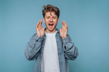 Genç adamın portresi coşkuyla bağırıyor ve açık mavi arka planda dururken heyecanını ifade ediyor.