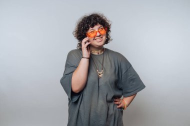 Şaşırmış kıvırcık saçlı genç bir kadının portresi açık arkaplanda bir telefon görüşmesi yapıyor.