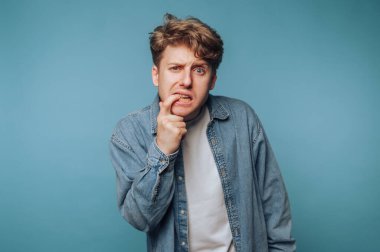 Genç adamın portresi açık mavi arka planda şaşkın bir ifade sergiliyor.