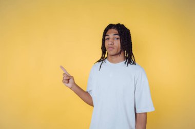 Genç adamın portresi kendine güvenerek kenarda duruyor. Sarı arka planda bilgi veya yön gösteriyor.