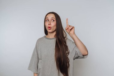 Genç bir kızın portresi, parlak arka plan hakkında bir fikri varmış gibi düşünceli bir ifadeyle parmağını kaldırır.