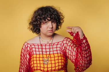 Ciddi bir ifadeyle genç bir kadının portresi, sarı arka planda bir önem ve kararlılık duygusu taşıyarak kenarı işaret ediyor.