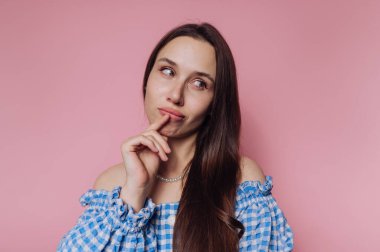 Pembe arka planda dudaklarına neşeyle dokunurken genç bir kadının portresi