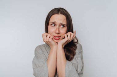 Genç bir kızın portresi endişeyle yüzünü açık arkaplanda tutuyor.