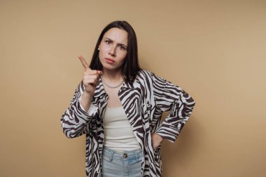 Genç bir kadının portresi, sakin sarı arka planda parmağını kameraya doğrulturken hayal kırıklığına uğramış bir ifade sergiliyor.