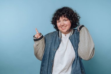 Genç bir kadının portresi heyecan verici bir poz ve mavi arka planda neşeli bir ifade sergiliyor.