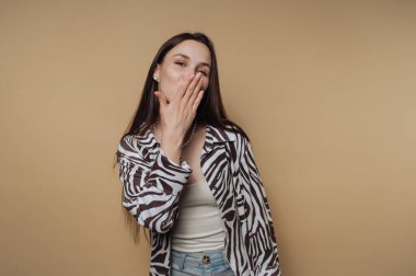 Zebra desenli tişörtlü neşeli genç bir kadının portresi öpüşüyor, sakin sarı arka planda neşe ve canlılık sergiliyor.