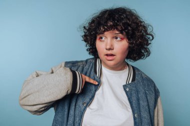 Genç bir kadının portresi, mavi arka plandaki heyecan ve merakı yansıtan ceketlerini işaret eder.