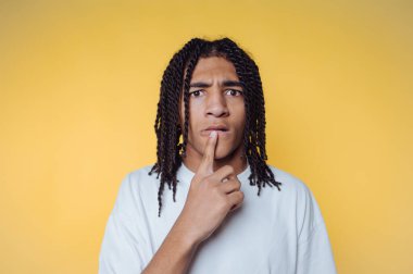 Dudaklarında bir parmak olan genç adamın portresi, sarı arka planda bir tefekkür ya da sorgulama bakışı sergiliyor.