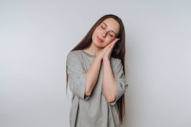 Genç bir kadının portresi yavaşça gözlerini kapatır ve uyur gibi poz verir, hafifçe arka planda huzur ve huzur verir.