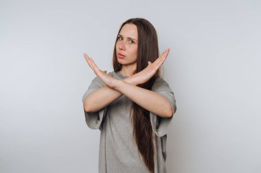 Genç bir kadının portresi, kollarını negatif bir şekilde kavuşturarak tasvip etmediğini gösterir. Işık arka planında dur işareti gibi.