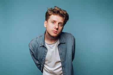 Genç adamın portresi, derin derin kameraya bakar. Açık mavi arkaplanda bir ciddiyet ve içgözlem anı yakalar.