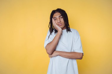 Genç adamın portresi düşünceli bir ifadeyle duruyor, sarı arka plandaki duygularını yansıtıyor.