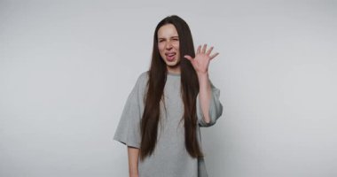 Neşeli genç bir kadın neşe ve yaratıcılığını ifade eder. Kişiliğini, parlak sarı arka plandaki eğlenceli jestlerle gösterir.