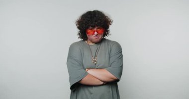 Çapraz kollu düşünceli genç bir kadın düşünceli bir şekilde beyaz arka plan üzerine düşünceli, iç gözlem ve tefekkür yapıyor.