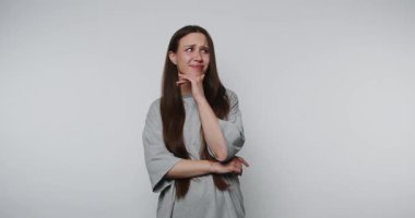 İnce bir gülüşü olan düşünceli bir insan, beyaz arka planda tefekkür ve yansıma yapar.