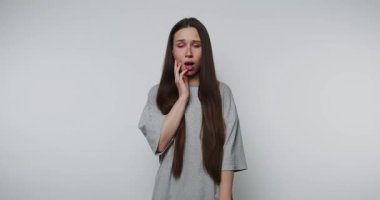 Genç bir kadın elini kalbinin üzerine koyar, şaşkın ve şaşkın, beyaz arka planda gerçek bir şaşkınlık reaksiyonu yakalar.