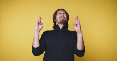 Genç adam şakacı bir sırıtışla kaslarını esnetir, sarı arka planda güvenle durur.