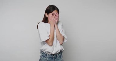 Genç bir kadının elleri ile yüzünü kapattığı görüntüler, arka planda güçlü bir umutsuzluk ya da ezilme duygusunu resmediyor.